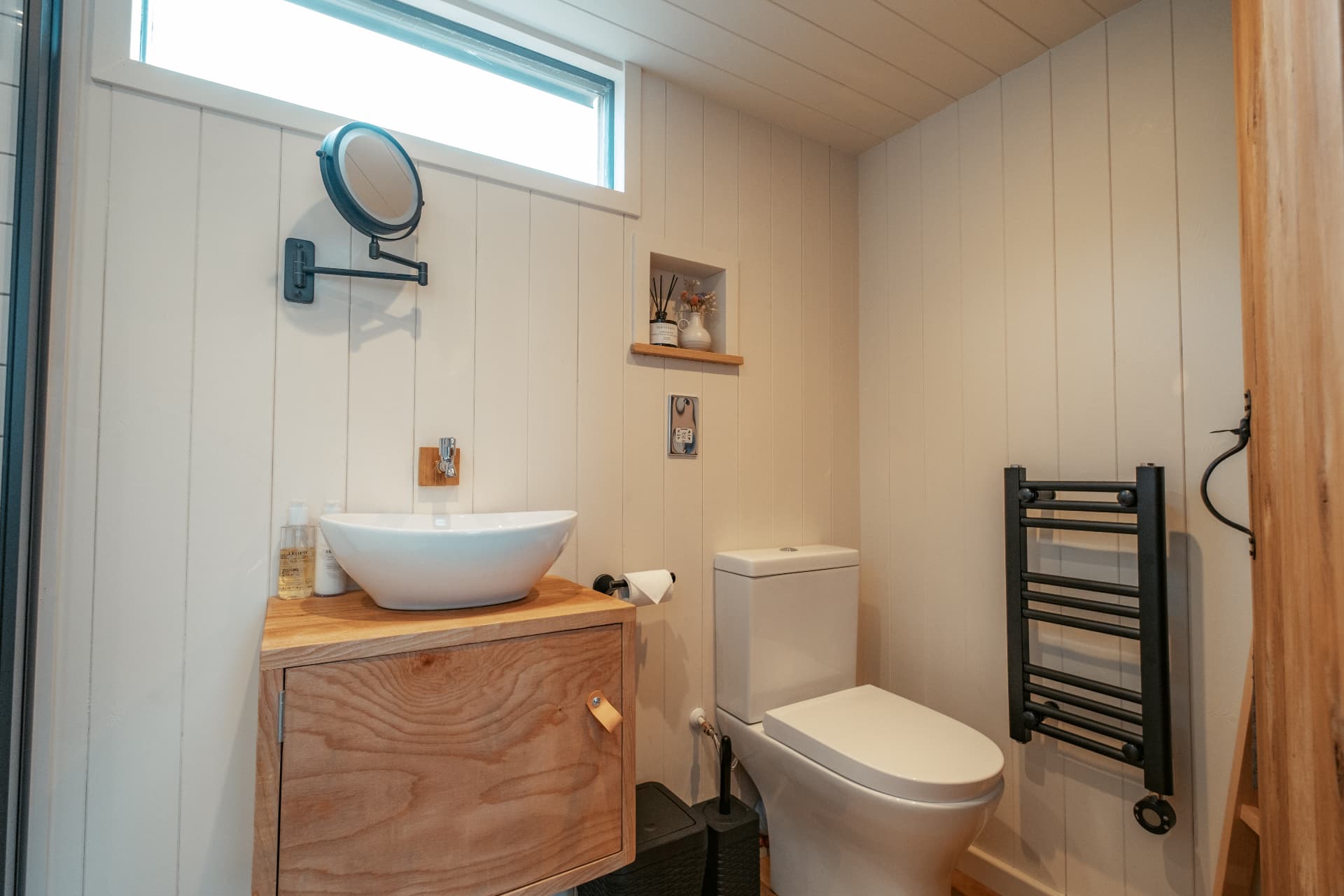 The Bothy bathroom — basin on an oak cabinet, heated towel rail and skylight above