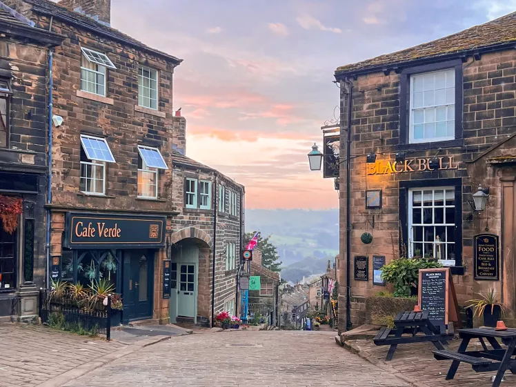 Haworth's cobbled main street at sunset, with the Black Bull pub