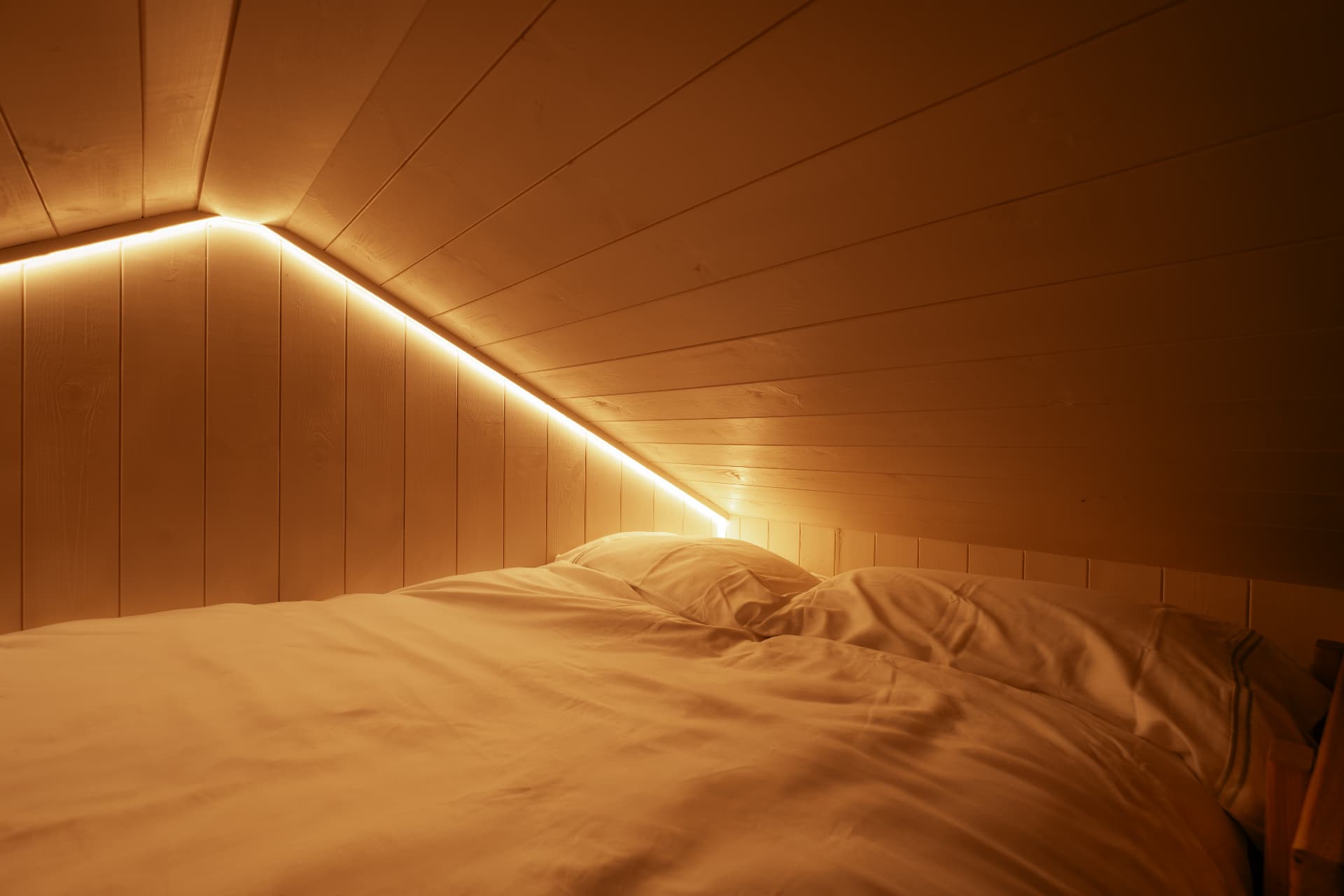 The mezzanine bed tucked under the eaves of The Bothy, glowing with warm light