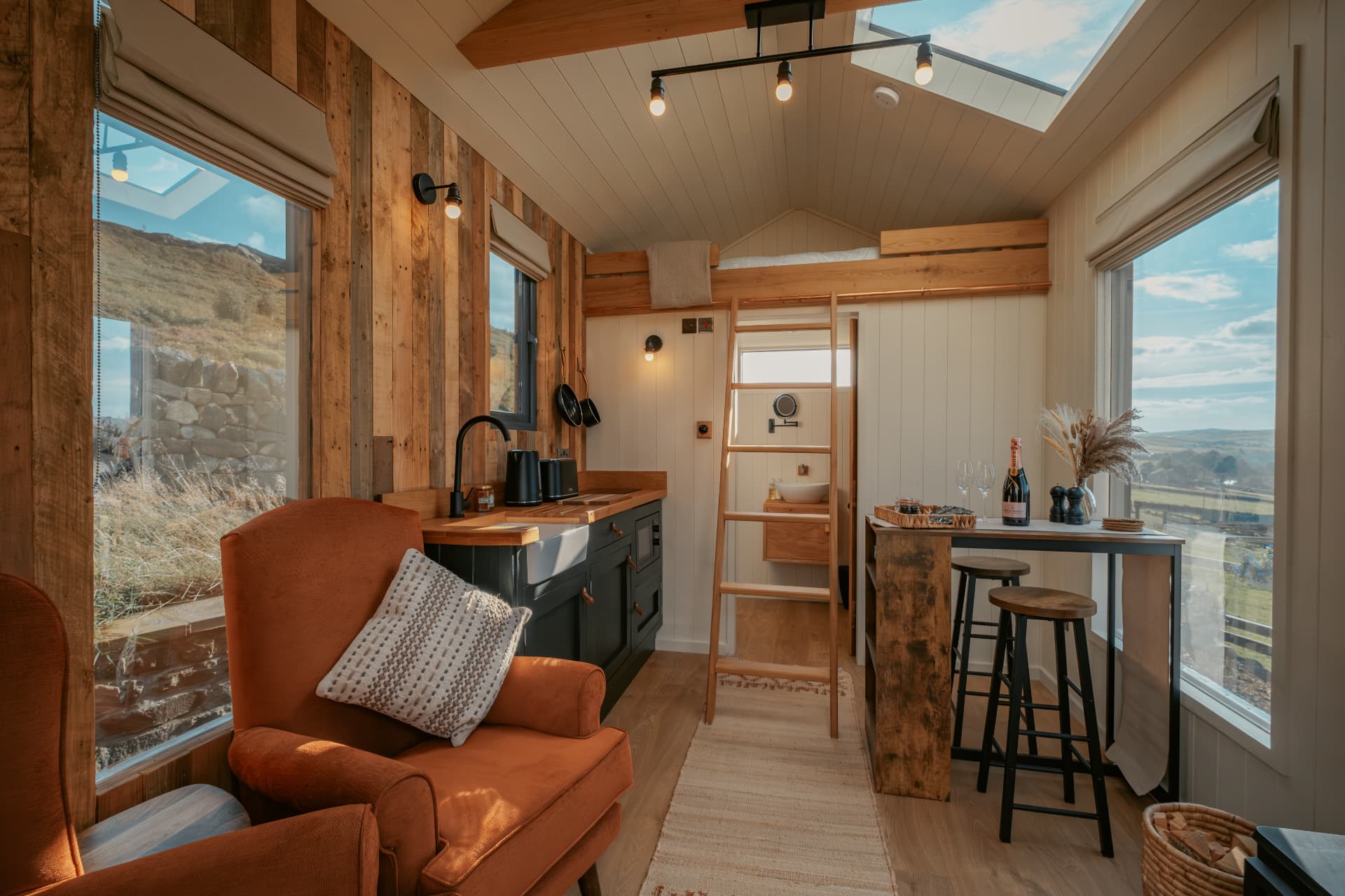 Inside The Bothy looking out over the valley — wood burner, breakfast bar and window seats on either side